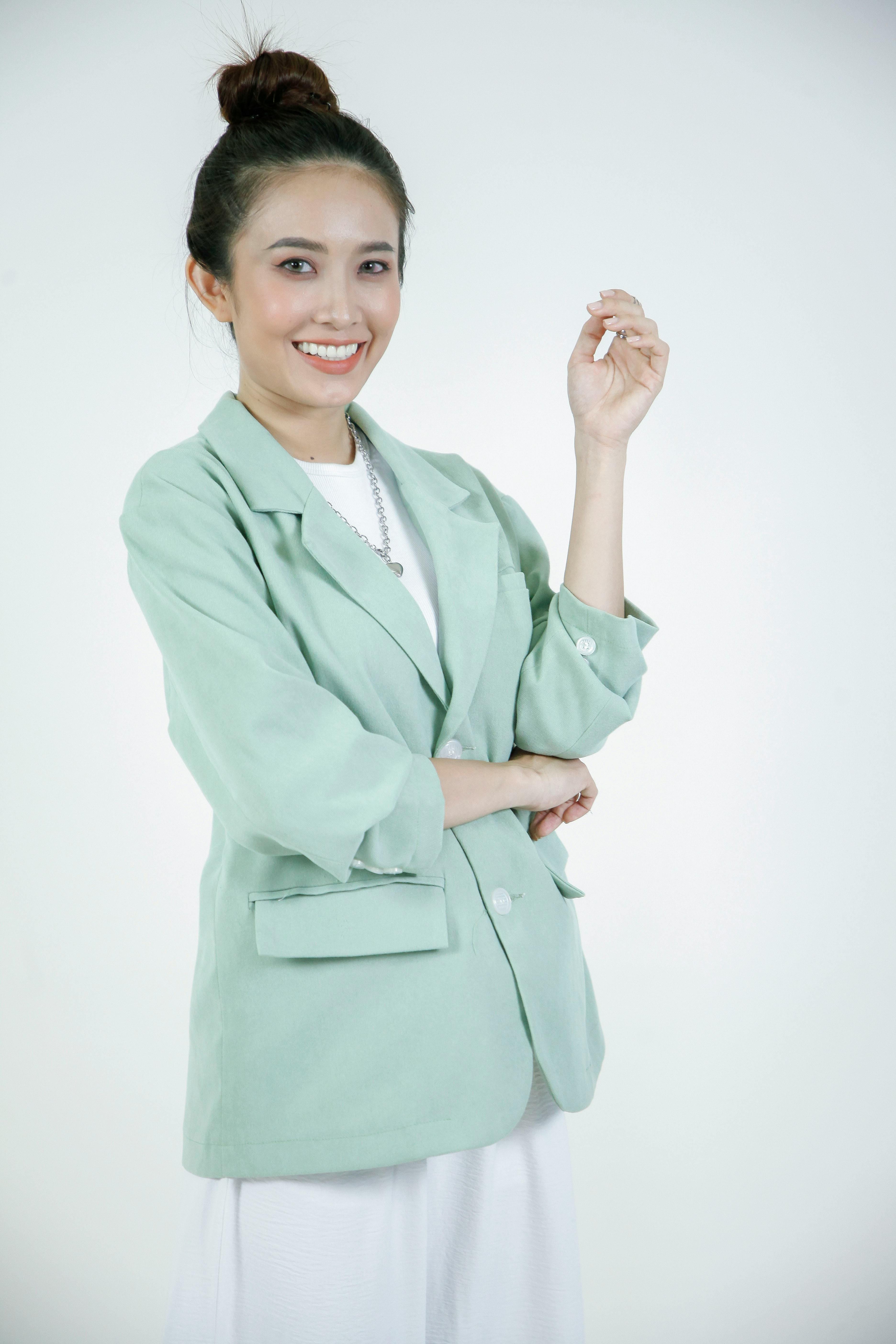 Kostenlos Porträt einer lächelnden Frau in einem mintgrünen Blazer vor weißem Hintergrund. Stock-Foto