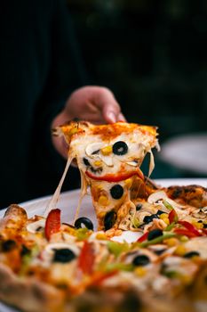 Close-up of a pizza with various toppings including olives and peppers.