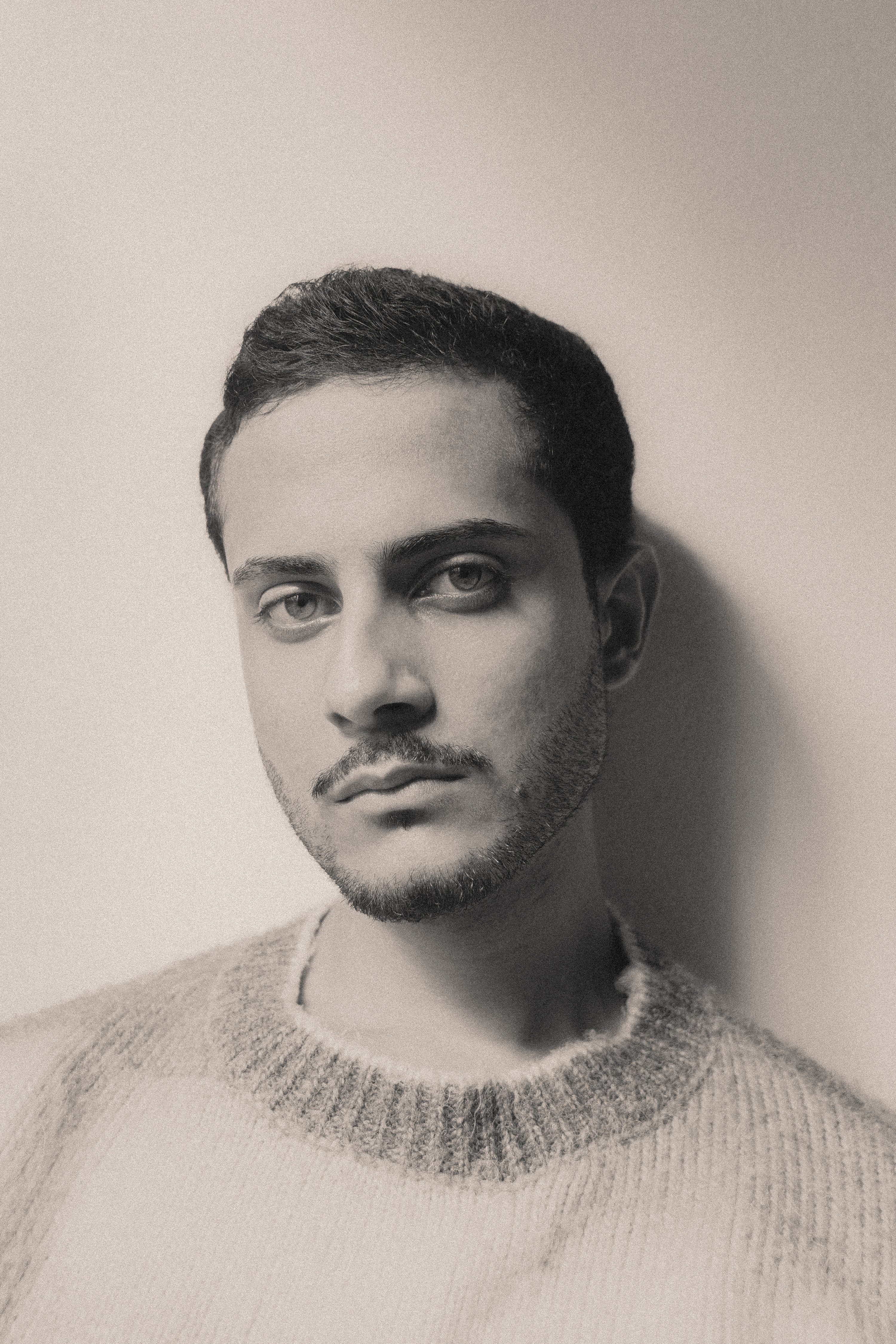 Introspective young man in knitted sweater, classic black and white portrait.