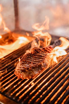 Close-up of a juicy steak sizzling on a hot grill surrounded by dancing flames.