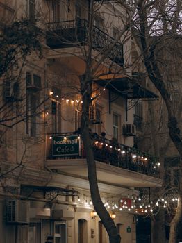 Charming cafe balcony adorned with string lights in urban setting during evening.