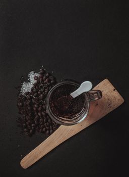 黑色背景上，黑咖啡、咖啡豆和勺子构成了一幅极简静物画
