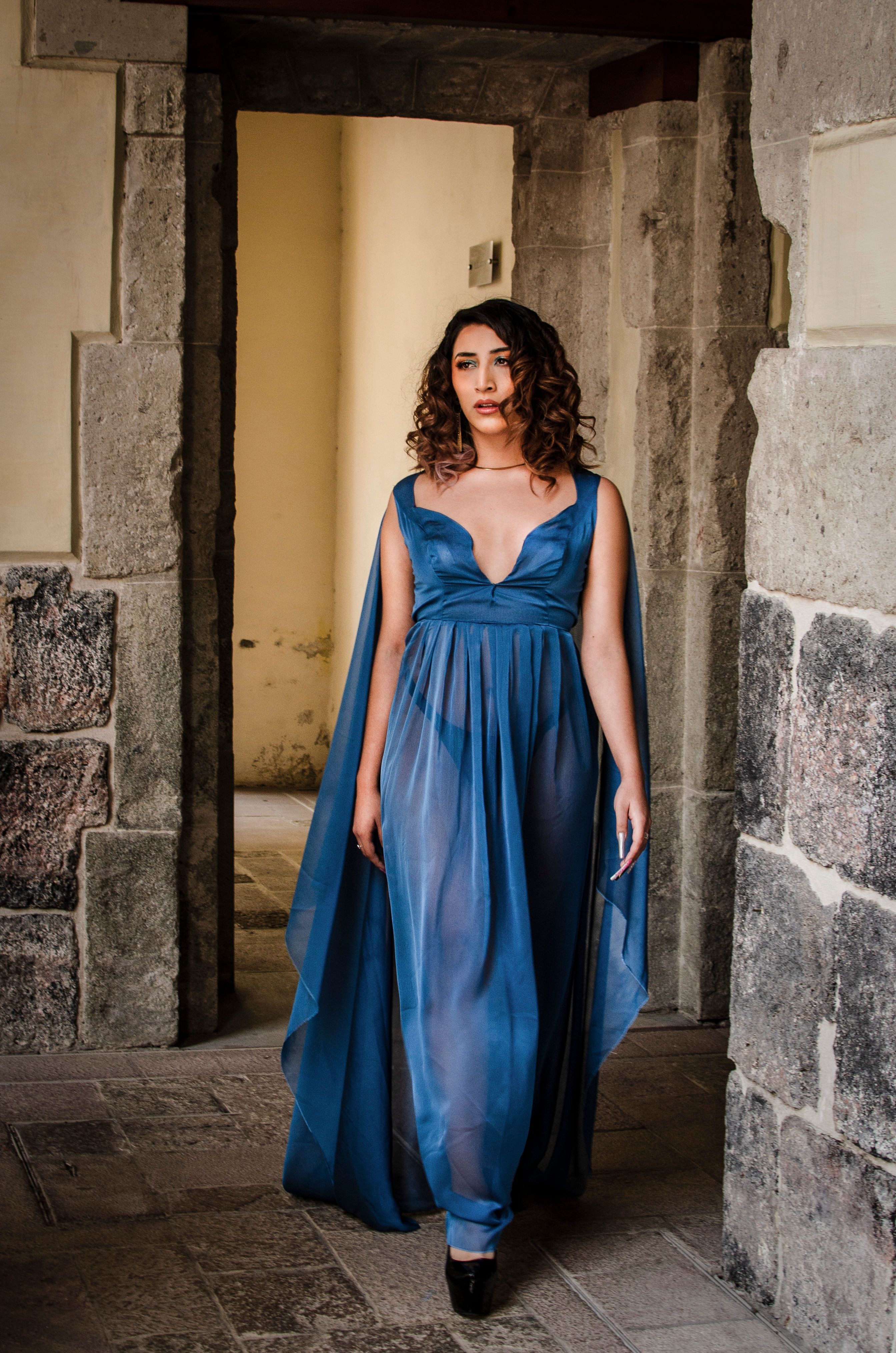 Elegant Woman in Blue Gown in Stone Corridor · Free Stock Photo