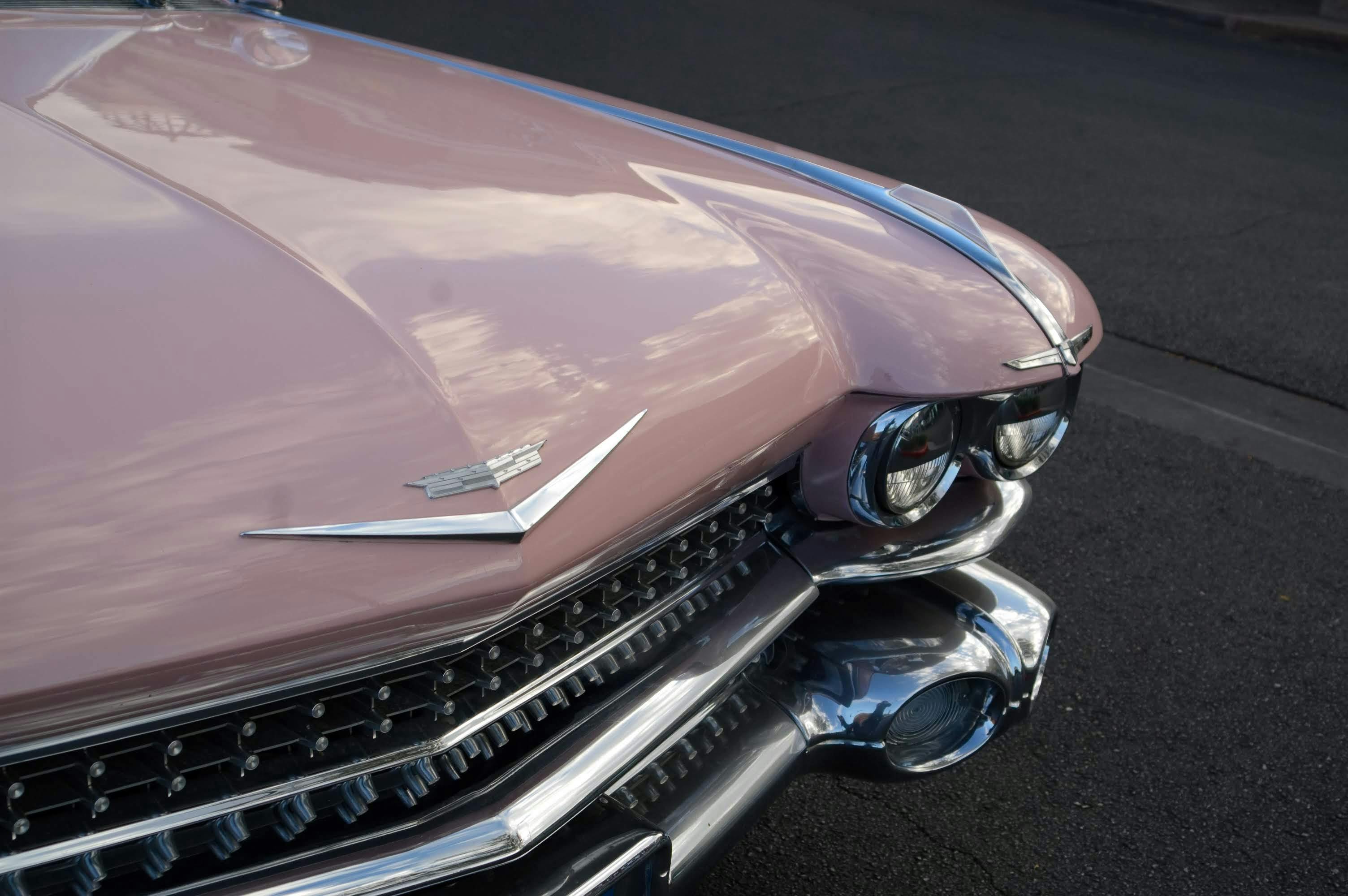 A vintage pink Cadillac showcased outdoors in Las Vegas, highlighting its classic design and chrome details.