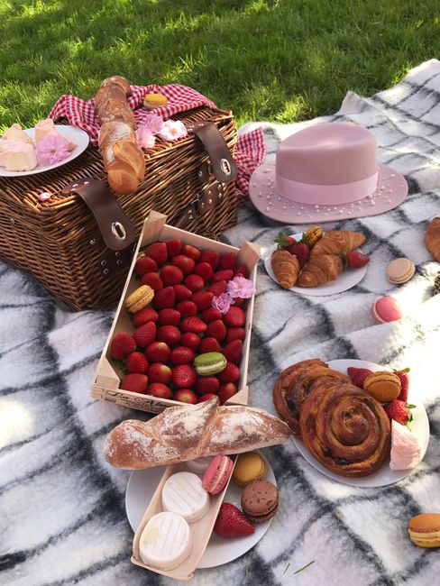 Delightful picnic setup with fresh strawberries, baked goods on a plaid blanket outdoors.
