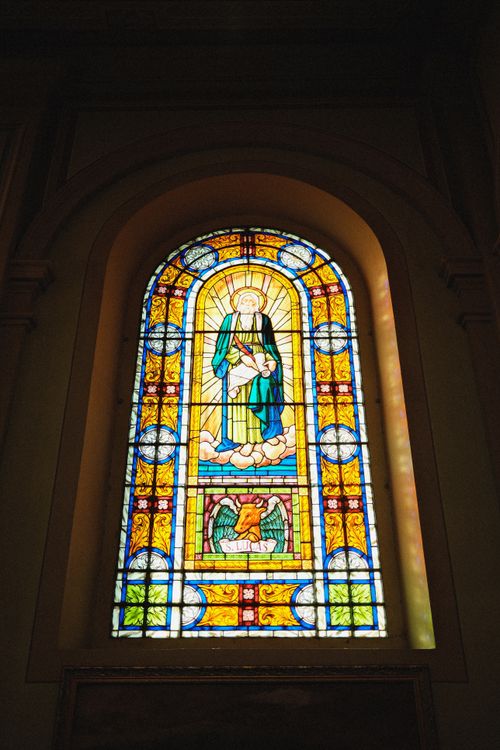 Free Colorful stained glass window depicting religious figures inside a church. Stock Photo