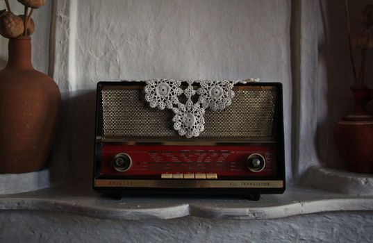 Classic vintage radio adorned with crochet lace set against a rustic background.