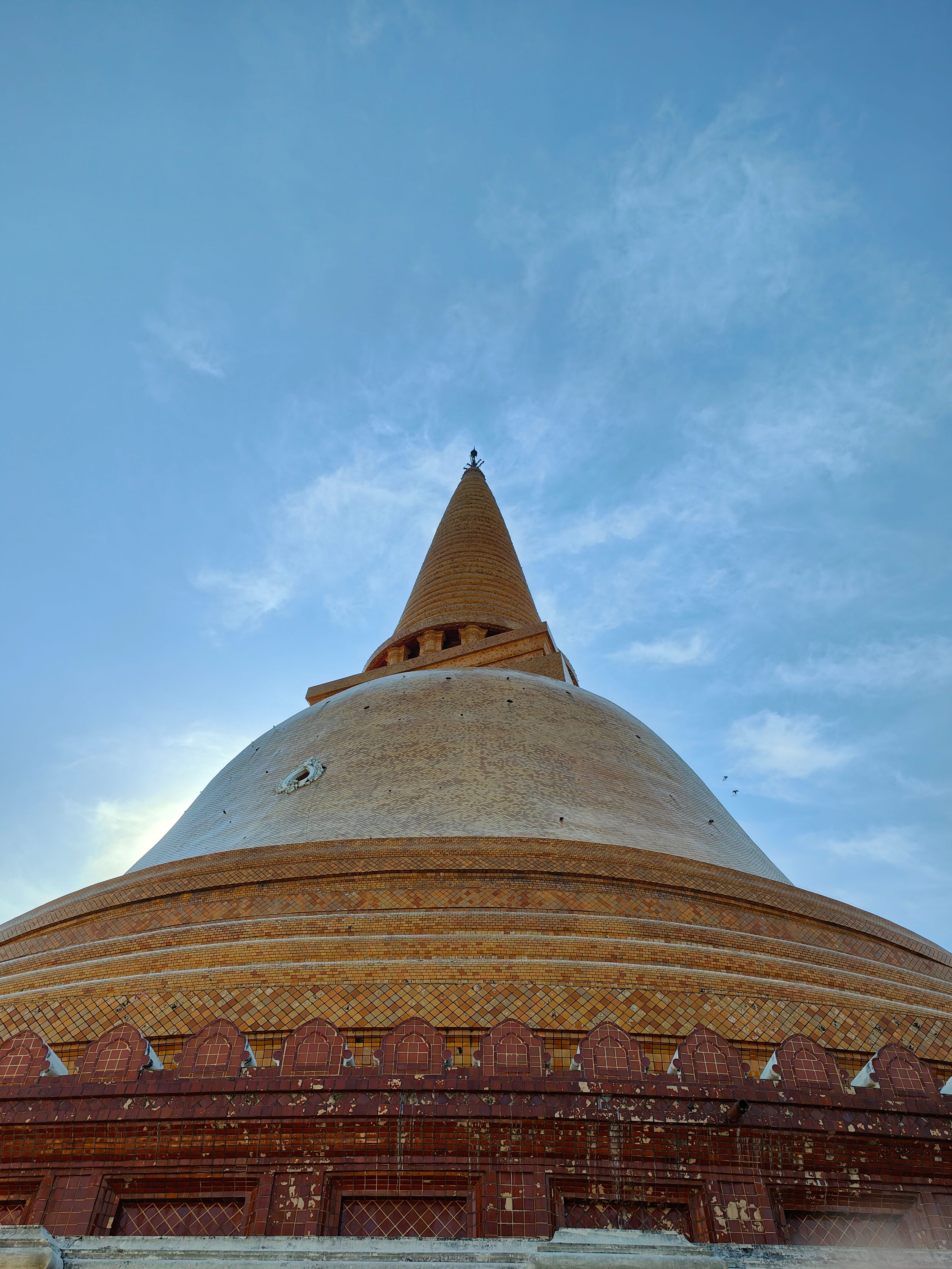 Striking upward view of Phra Pathom Chedi in Thailand beneath a vibrant blue sky.