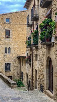 Picturesque stone houses with flower balconies on a narrow European street.