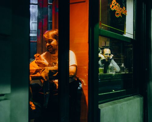 Free Two people enjoying a night inside a Saigon-themed café, with warm lighting and a relaxed atmosphere. Stock Photo