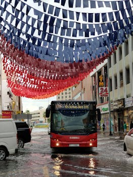 A vibrant street scene in Dubai with a bus and festive decorations under a rainy sky.