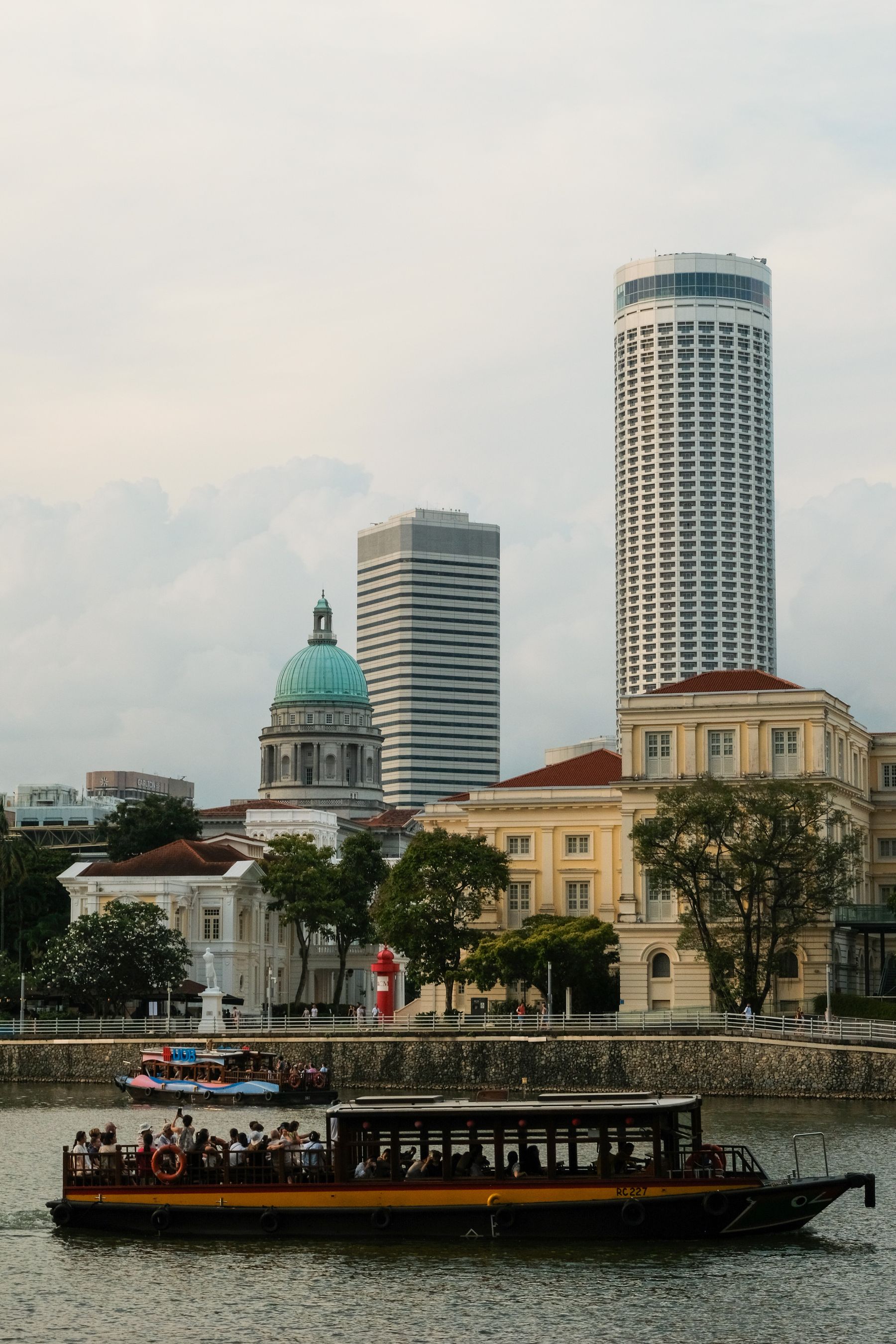 Passengers touring the Singapore River between civic buildings and modern towers