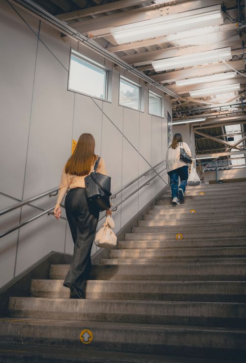 Free Two women walk up stairs in a modern Tokyo station, capturing urban life. Stock Photo
