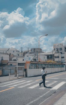 A person crosses a street in a quiet neighborhood in Kita Ward, Tokyo, under a vibrant blue sky.