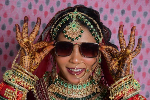 A vibrant South Asian bride with intricate mehndi, traditional jewelry, and sunglasses.