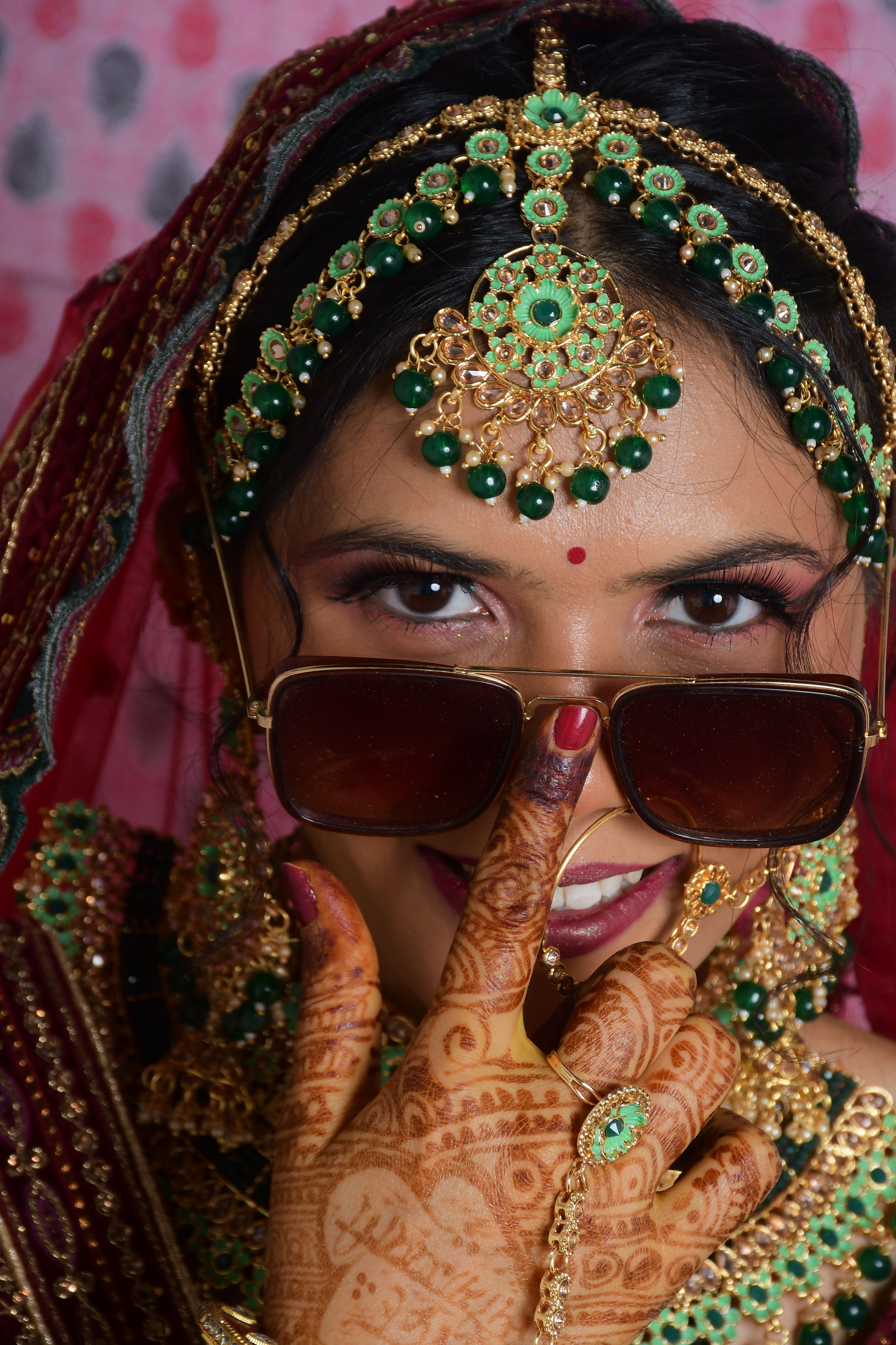 A fashionable South Asian bride in traditional attire, adorned with jewelry and henna.