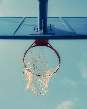 A minimalist view of a basketball hoop against a bright blue sky in Kenitra, Morocco.