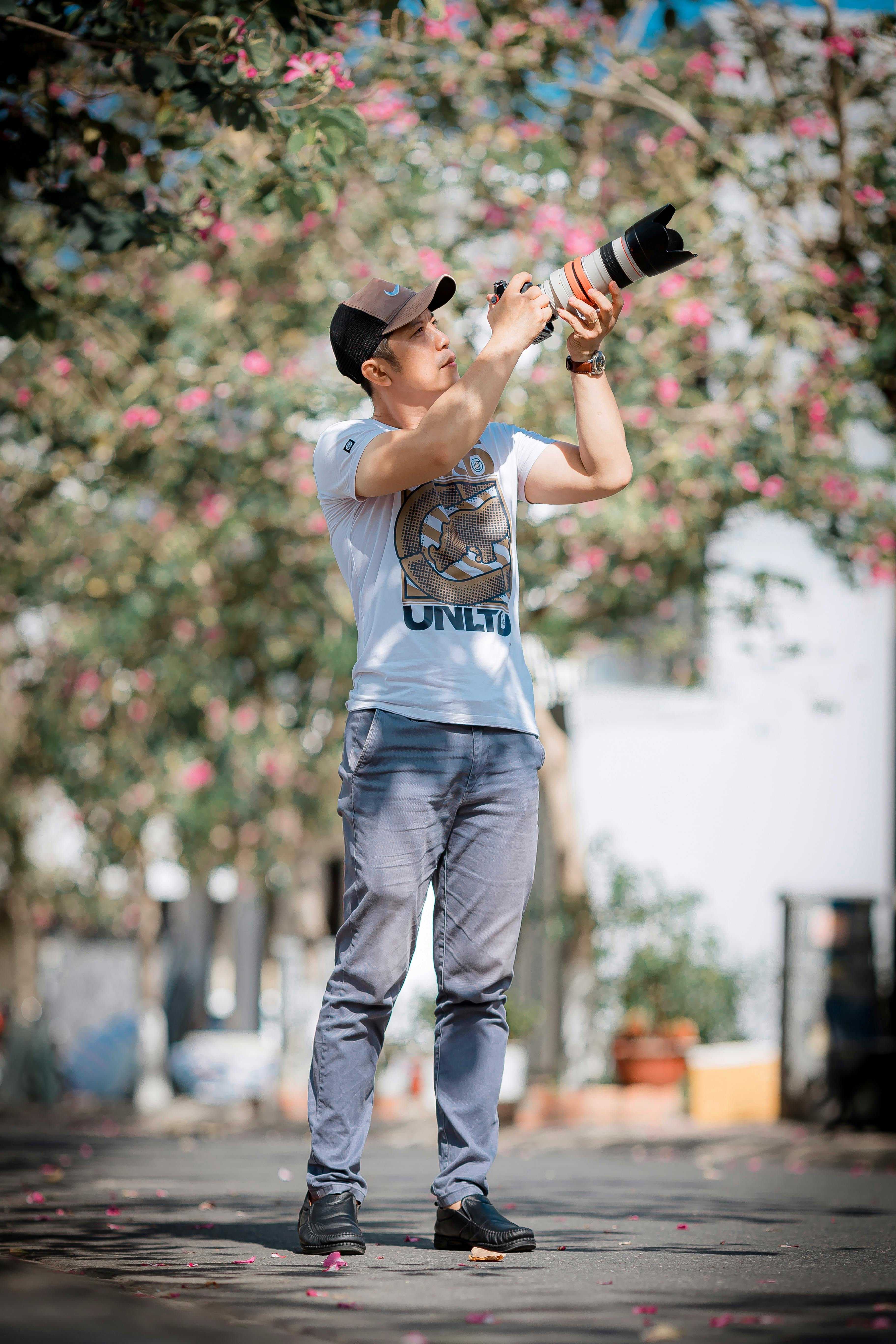 Man photographing spring blossoms with long lens. Bright, creative capture.
