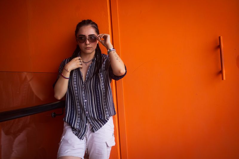 Woman in sunglasses against a bold orange wall — photo by Miguel Del Angel Villegas on Pexels
