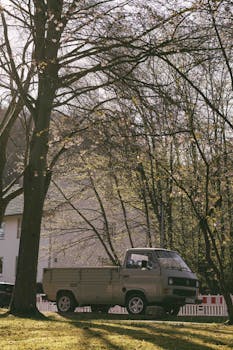 Classic beige truck parked in a serene rural area under tree shadows, capturing a peaceful spring day vibe.