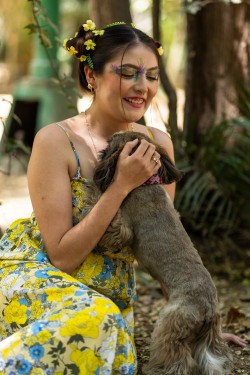 Free A Latina woman with spring floral makeup enjoying a playful moment with her dog in a vibrant garden. Stock Photo