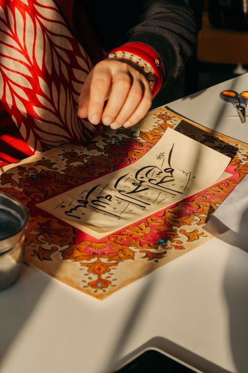 Free Craftsman creating intricate calligraphy art with vibrant patterns under sunlight. Stock Photo