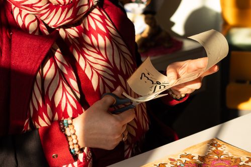 Free A person engaged in paper cutting craftwork, highlighted by natural sunlight. Stock Photo