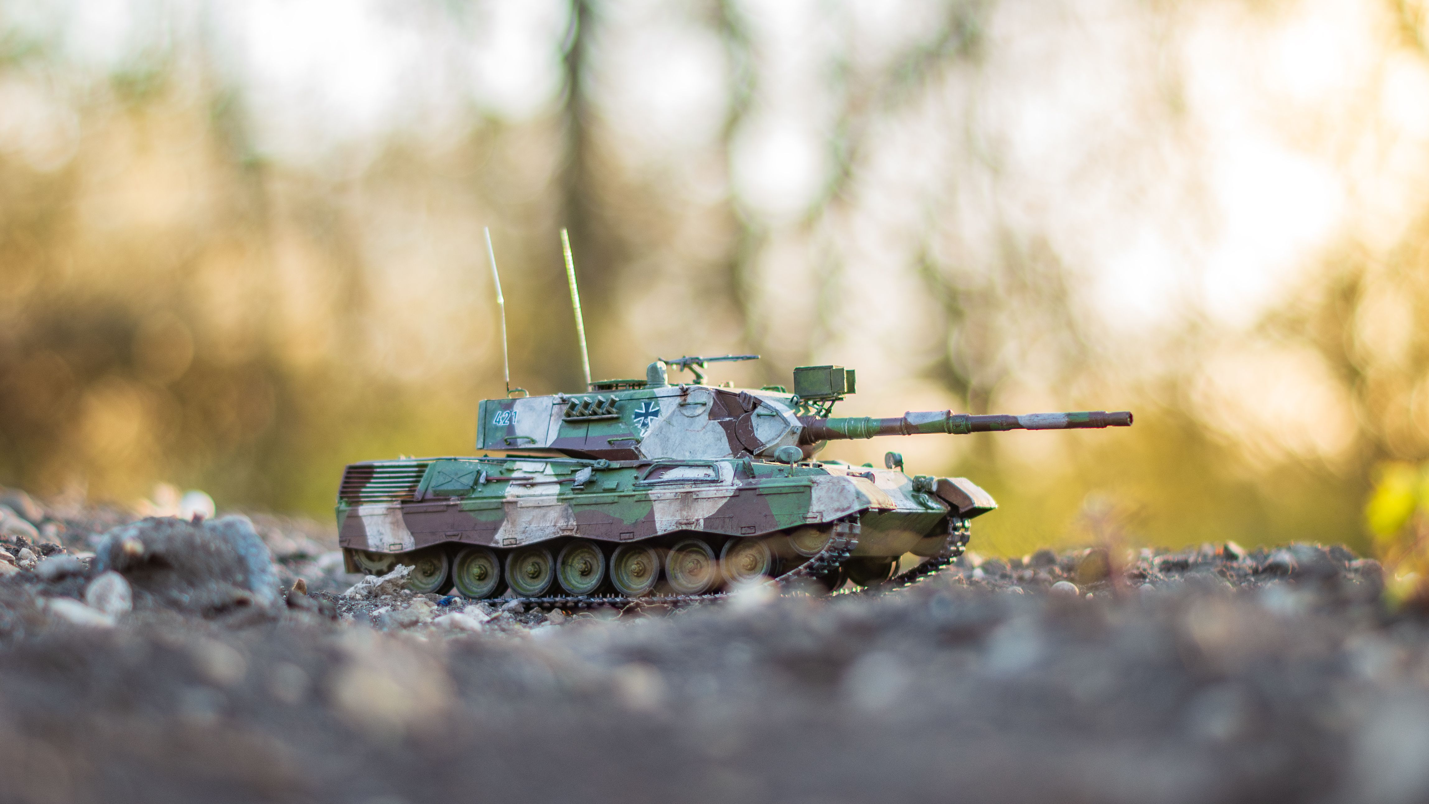 Close-up of a miniature military tank model on rough terrain outdoors with natural background.