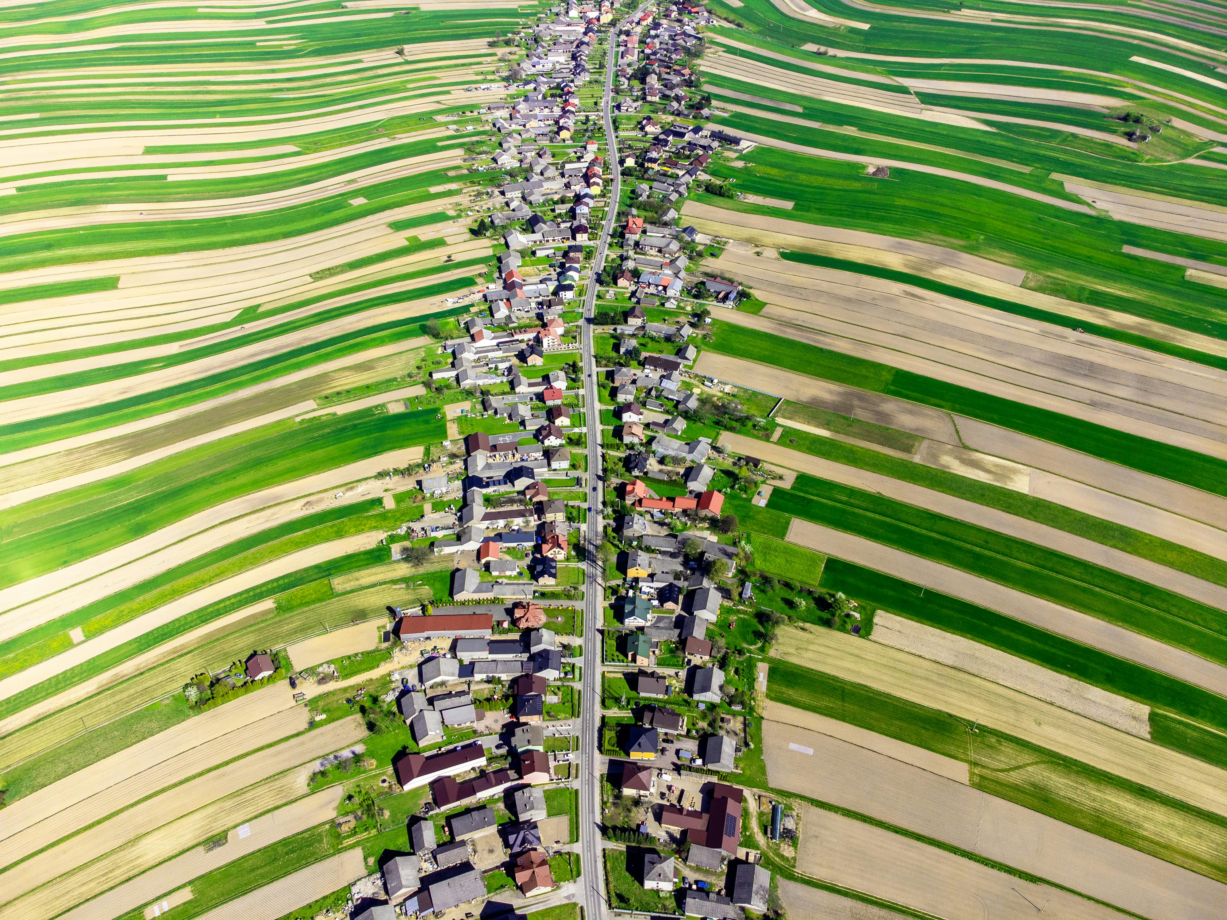 Stunning aerial view of a vibrant Polish village surrounded by lush fields in spring.