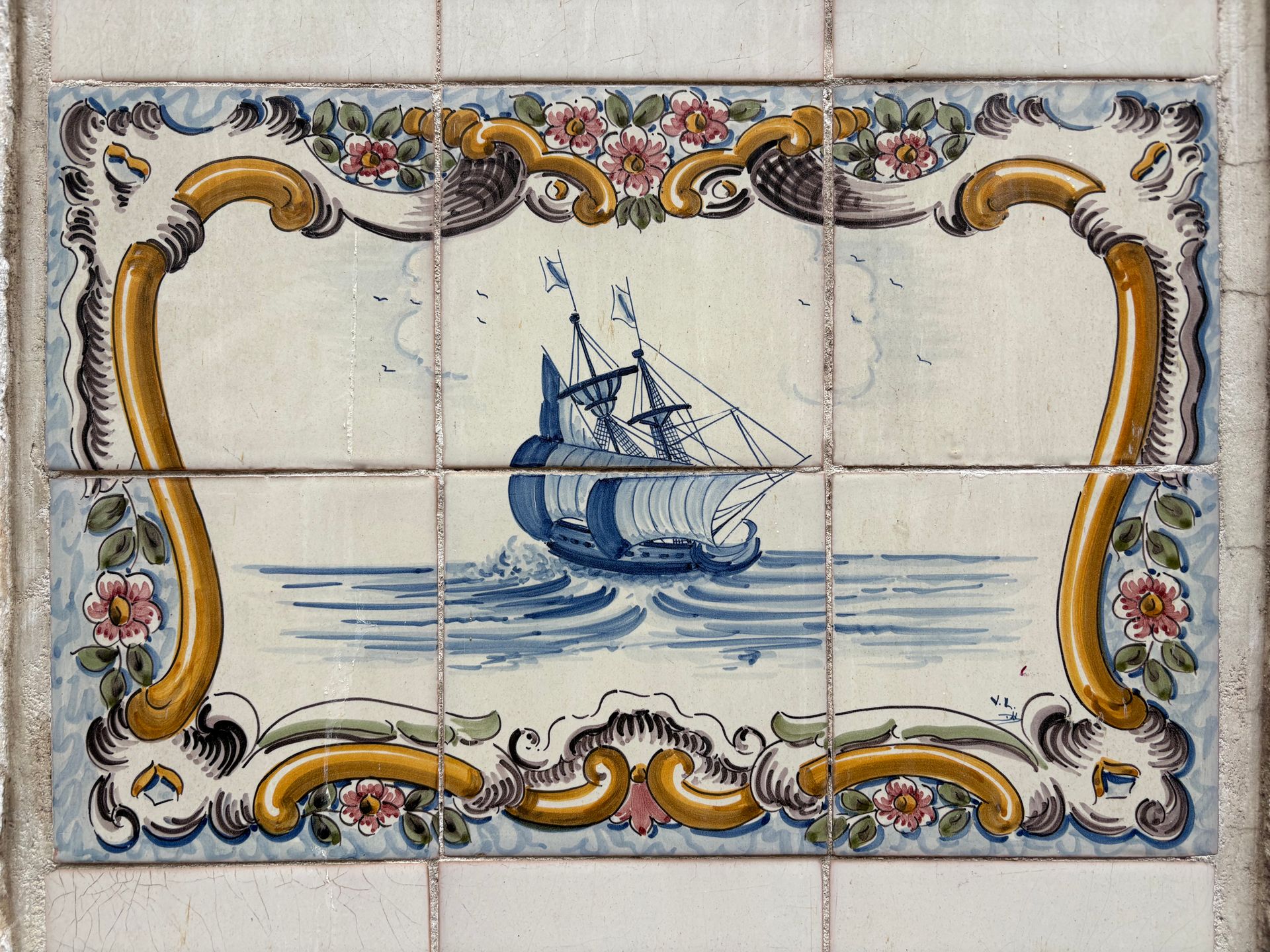 Decorative azulejo tile in Lisbon depicting a classic ship in ornate floral patterns.