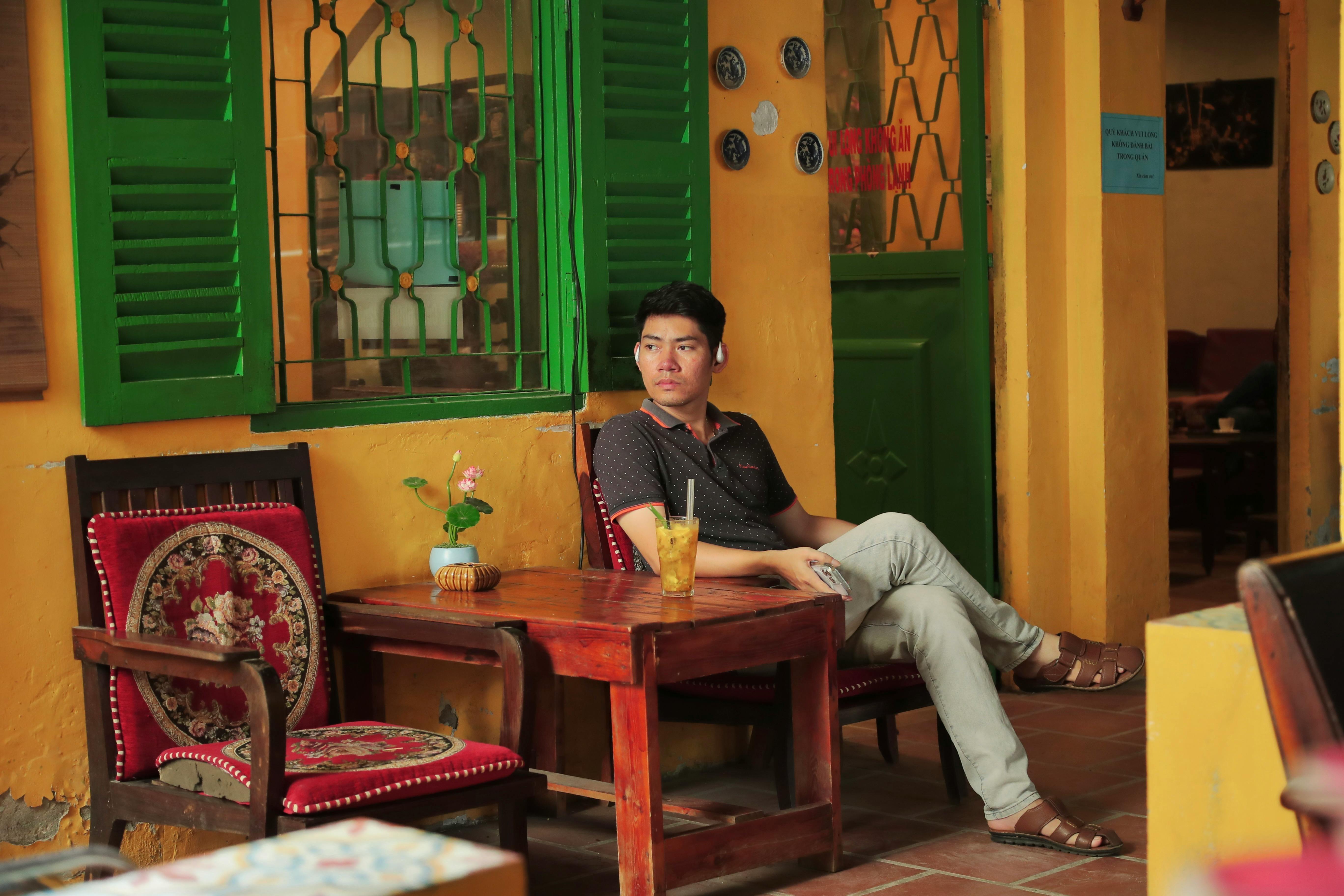 Gratuit Bărbat așezat într-o cafenea în stil vintage, cu decor vibrant și răcoritoare. Fotografie de stoc