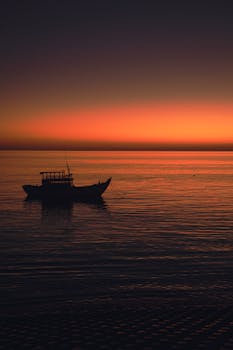 Serene silhouette of a boat on Bình Thuận sea at sunset, Vietnam.