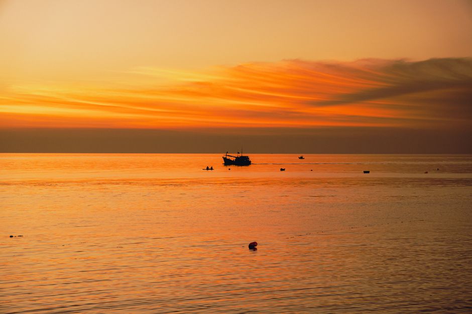 Captivating sunset view of Bình Thuận coast with vibrant sky and silhouettes of fishing boats.