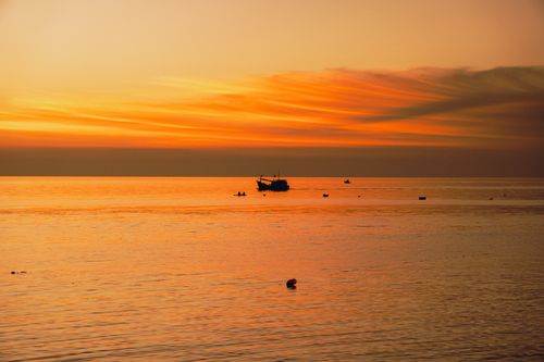 Free Captivating sunset view of Bình Thuận coast with vibrant sky and silhouettes of fishing boats. Stock Photo