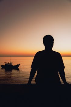 A silhouette of a person looking at the sea during sunset in Bình Thuận, Vietnam.