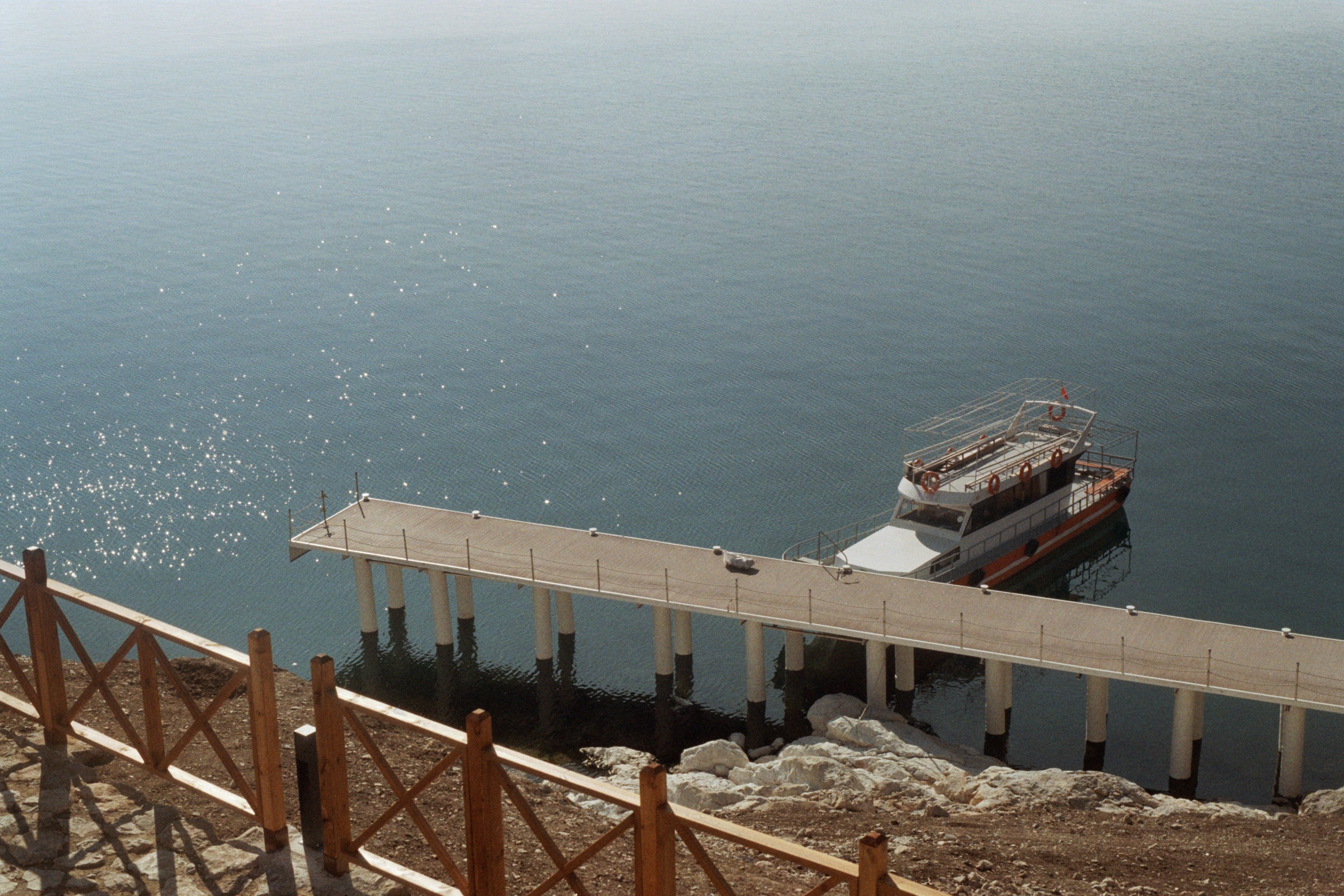A serene view of a boat dock on Lake Van, Turkey, with calm waters and distant hills.