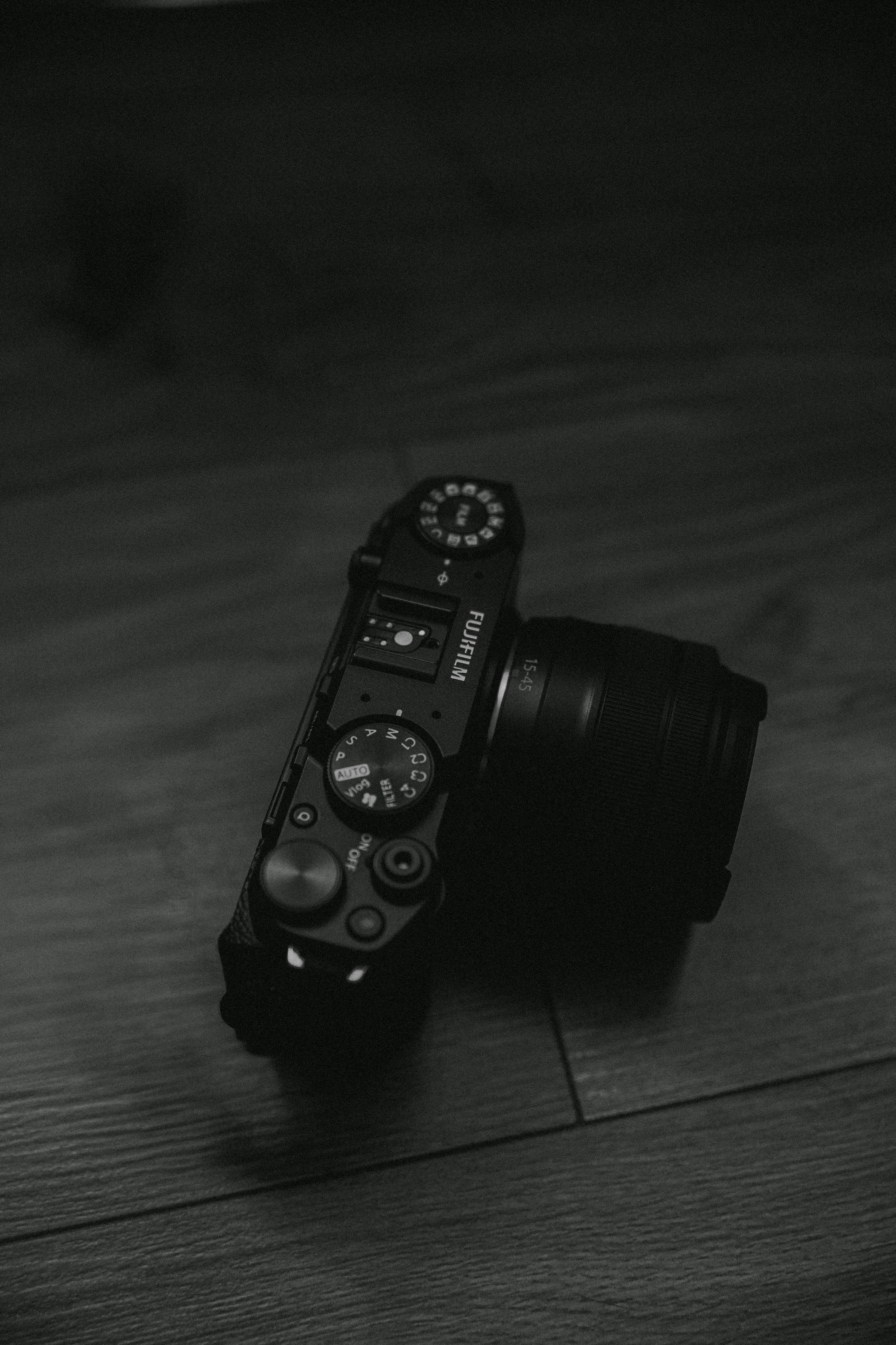 Ücretsiz Ahşap bir yüzey üzerinde karmaşık detaylara sahip bir DSLR fotoğraf makinesinin tek renkli görüntüsü. Stok Fotoğraflar