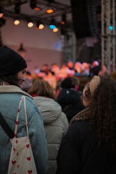 People enjoying a festive evening at an outdoor Christmas market in Bratislava with live music.