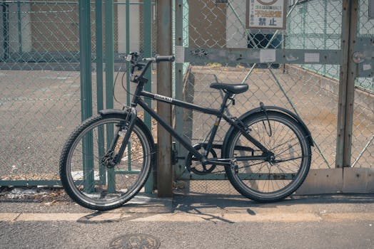 A vintage-style bicycle leaning against a chain-link fence in Chiyoda, Tokyo.