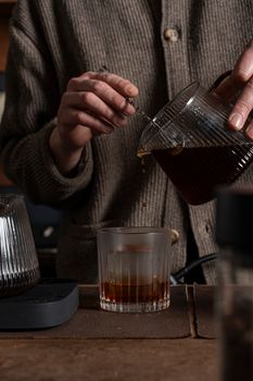 Barista pouring freshly brewed coffee into a glass, creating authentic coffee moment.