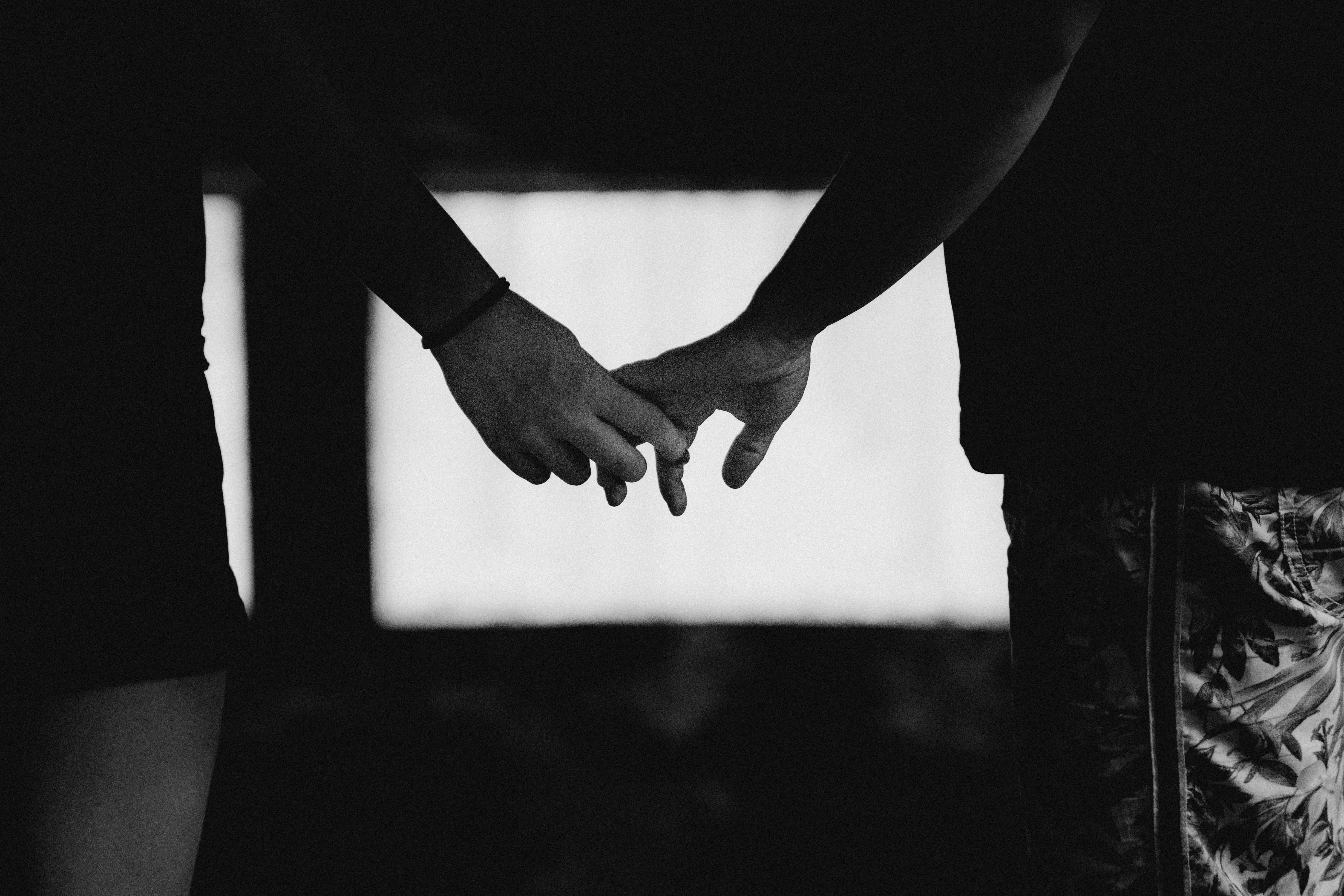 Silhouette of two people holding hands at dusk, with a soft halo in the background, symbolizing the deep connection and security desired by Moon-Pluto aspects