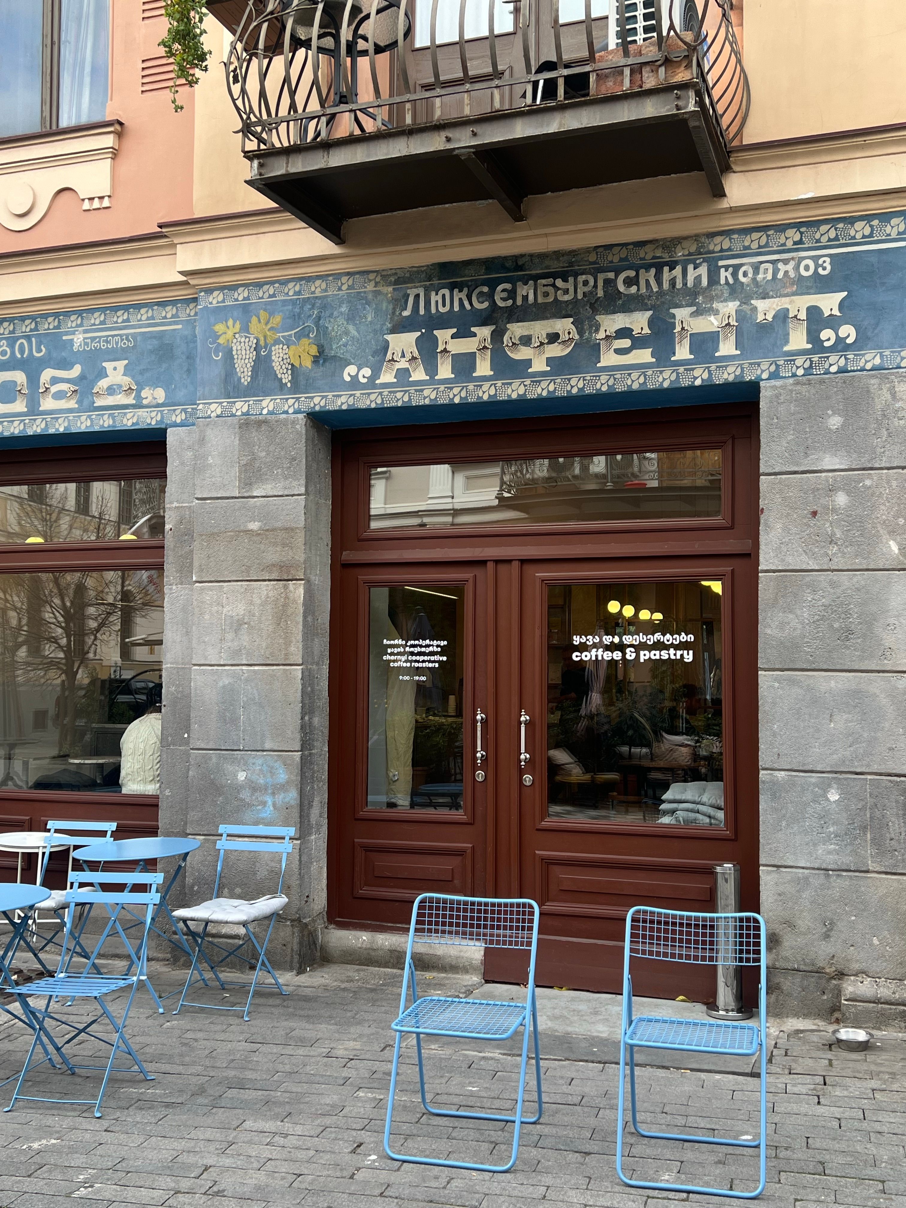Cozy cafe entrance with blue chairs outside, nestled in historic architecture.