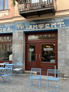Cozy cafe entrance with blue chairs outside, nestled in historic architecture.