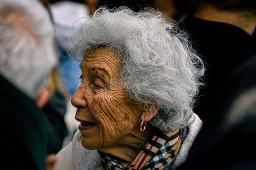 Primo piano di una donna anziana con i capelli grigi e una sciarpa, che esprime saggezza.