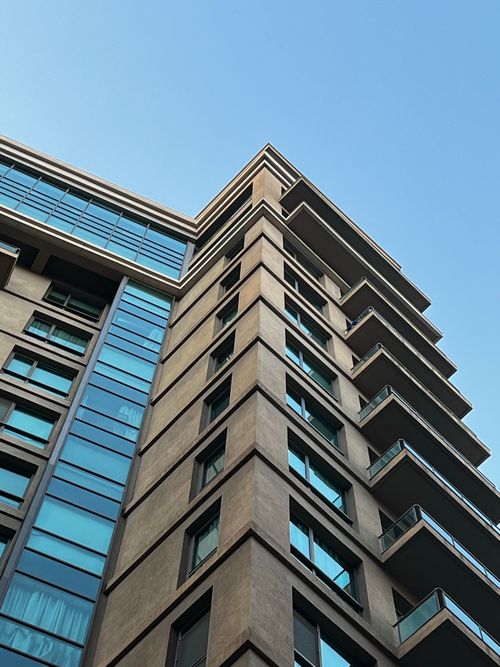 Free A contemporary high-rise building with glass windows under a clear blue sky. Stock Photo