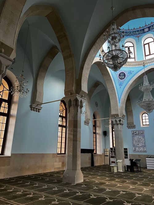 Free Spacious mosque interior featuring ornate chandeliers, archways, and detailed decor, offering a serene atmosphere. Stock Photo