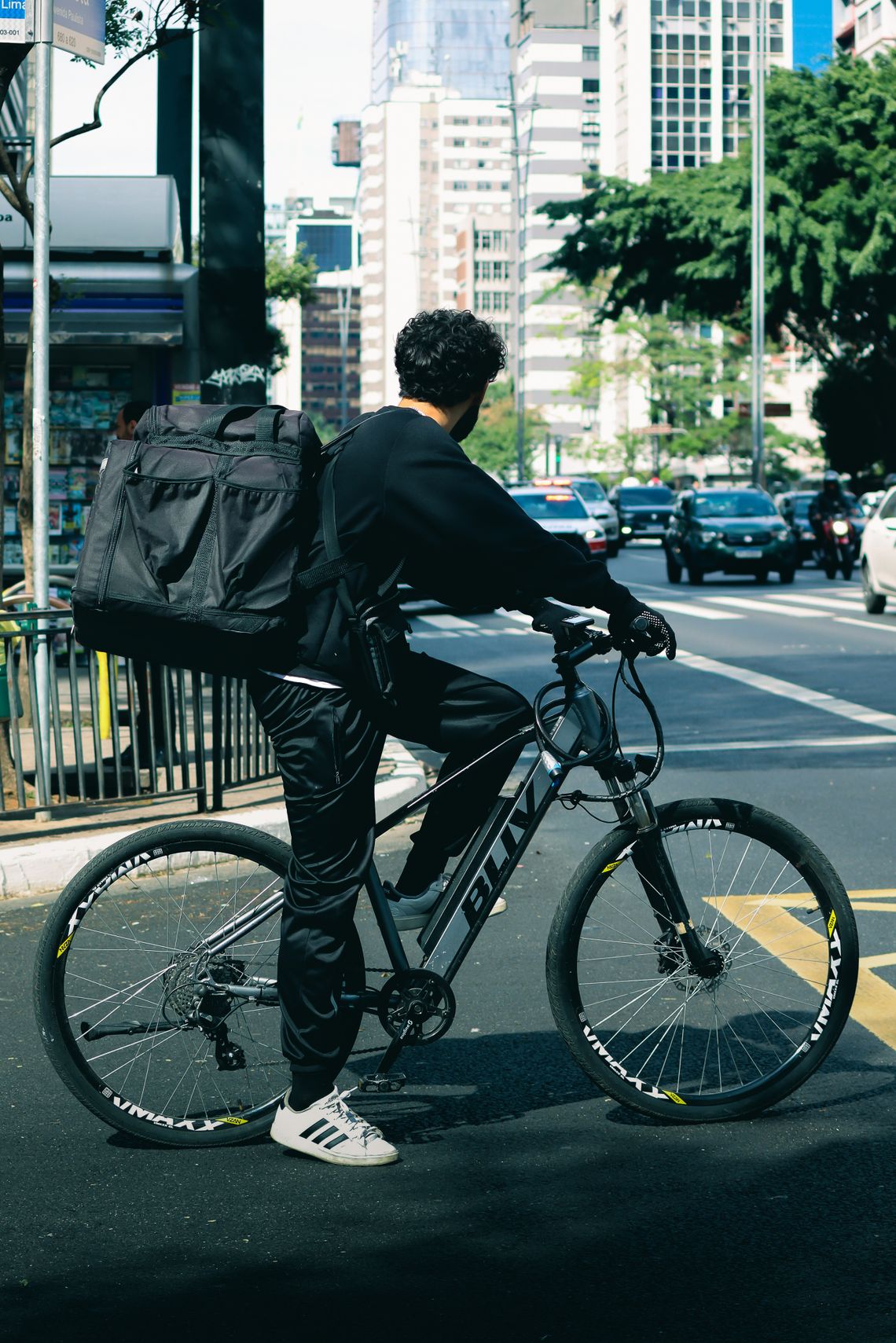 Helmeted bicycle delivery rider waiting at a busy city intersection