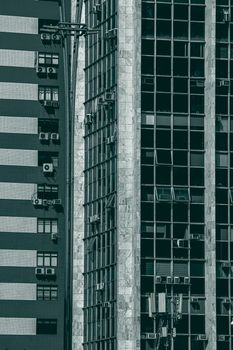 Close-up of a multi-story modern building facade featuring air conditioners and glass windows.
