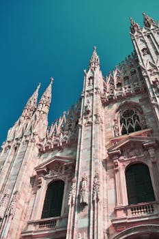 在晴朗的蓝天下，一座历史悠久的哥特式大教堂展现出低视角的错综复杂的尖顶和拱门