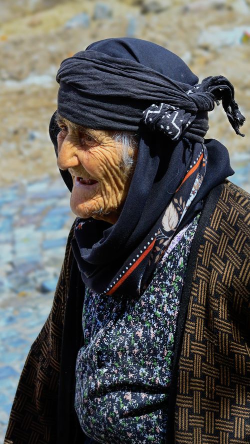 Free Portrait of an elderly woman in traditional clothing basking in daylight outdoors. Stock Photo